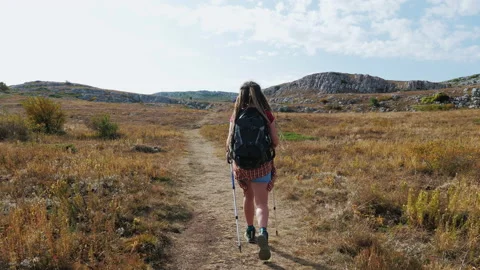 Girl with backpack and poles going through mountain plato Stock Footage 194492004