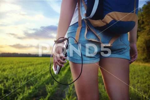 Girl with a backpack on a journey. Tourist holds in her hand a smartphone and Stock Photos