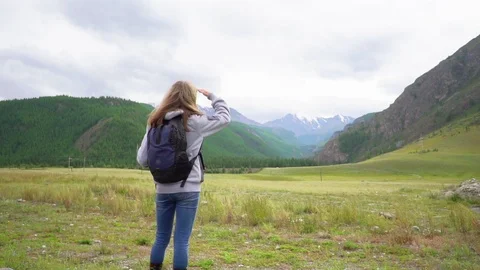 Girl with a backpack looking at the mountains Stock Footage 120726716