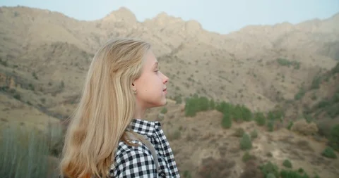 Girl with a backpack, looking through binoculars in the mountains in the fall. 4 Stock Footage 98777445
