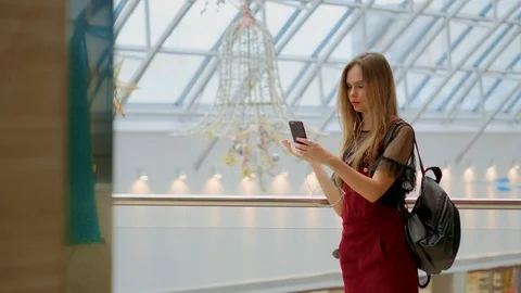 Girl with a backpack talking on video coll through headphones and a mobile phone Video stock 98753786