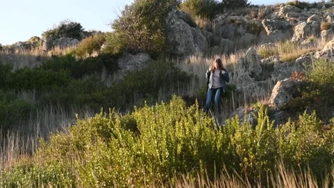A girl with backpack walking in the sun rays, hiking in mountain Stock Footage 131532829