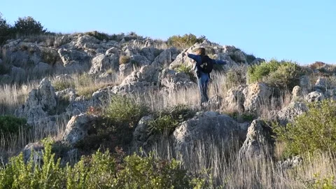 A girl with backpack walking in the sun rays, hiking in mountain Stock Footage 131556540
