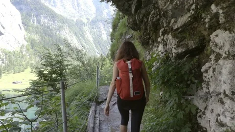 Girl with the backpack is walking through the path in the mountains Stock Footage 83525732