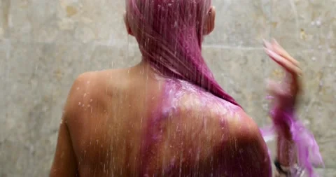 A girl with a bare back in bracelets washes her dyed pink hair in the shower Stock Footage 148725087