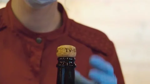 Girl bartender in cafe opens a bottle of champagne in medical disposable gloves Stock Footage 160649745