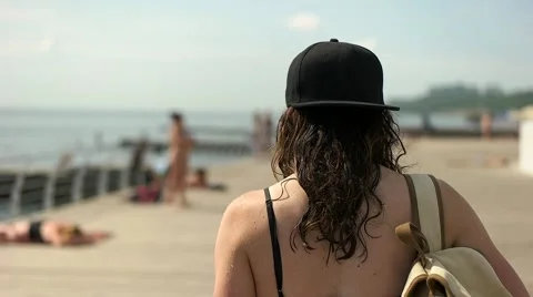 Girl in baseball cap with backpack walking on embankment Stock Footage 65293415