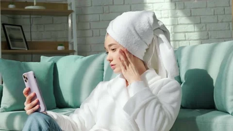 Girl in bathrobe and with bath towel on her head is making a selfie. Video stock 151480341