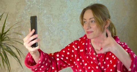 Girl in a bathrobe, using a smartphone make a video call Stock Footage 130282237