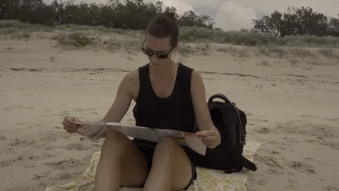 Girl on the beach reading a map Stock Footage 88446517