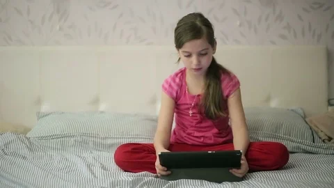 Girl on the bed educates herself on tablet Video stock 73359786