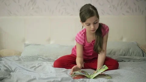 Girl on a bed reading a book Stock Footage 73359904