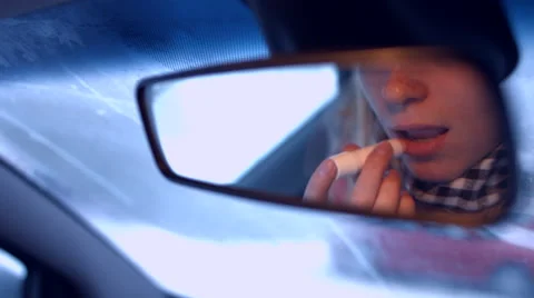 The girl behind the wheel of a car lipstick in the rearview mirror Stock Footage 59284525