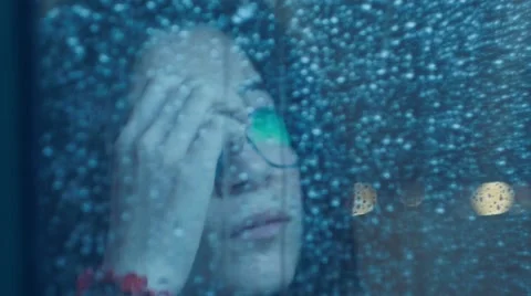 Girl behind window drinking an hot drink cup  in a rainy day. Shot in slowmotion Video stock 47891351