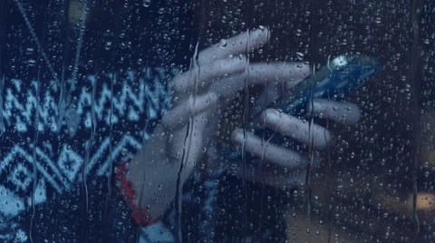 Girl behind window using smartphone in a rainy day. Shot in 4k (UHD) Stock Footage 47874131