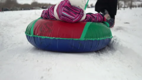 The girl is being rolled on an inflatable ring in the snow. A girl in warm Stock Footage 146283936