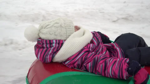 The girl is being rolled on an inflatable ring in the snow. A girl in warm Stock Footage 146284158