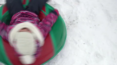 The girl is being spun on an inflatable ring in the snow. A girl in warm clothes Stock Footage 146284401