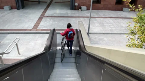 Girl with Bicycle going down on escalators Stock Footage 34225829