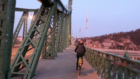 Girl on bicycle riding on a bridge. Camera pans to river Stock Footage