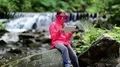 Girl in big glasses in shape of stars with tablet pc sits near river in forest HD Footage