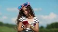 Girl in big sunglasses in the shape of hearts makes selfie on his smartphone HD Footage