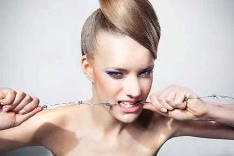 Girl bites the barbed wire, the concept Stock Photos