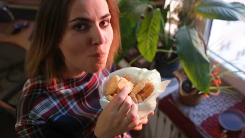The girl bites a round white cookie, enjoys the taste of baking and looks into t Stock Footage 87846005