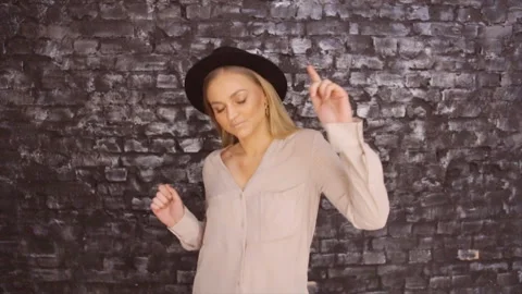 A girl in a black hat is dancing on the background of a textured wall Stock Footage 87260877