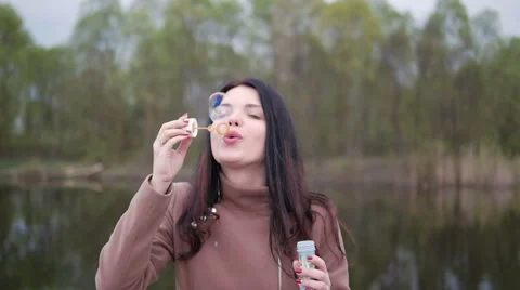 Girl blowing bubbles on a background of the river Stock Footage 62448062