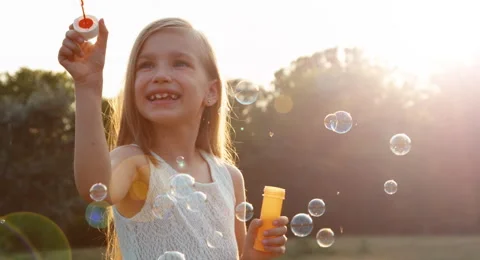 Girl blowing soap bubbles. Lens flare Stock Footage
