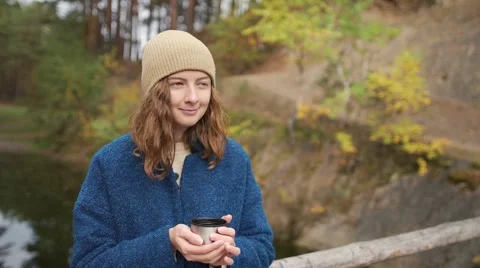 Girl in blue coat standing on the bridge and drinks hot tea. Stock Footage 68190832