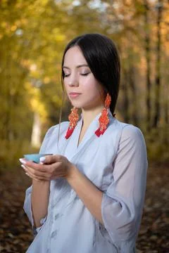 A girl in a blue kimono sits in the autumn forest and prepares tea Stock Photos