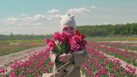 Girl with a bouquet of flowers on a tulips field Stock Footage