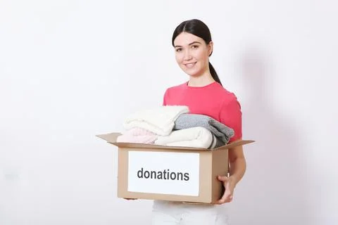 Girl with a box of donations on a colored background. place for text. Stock Photos