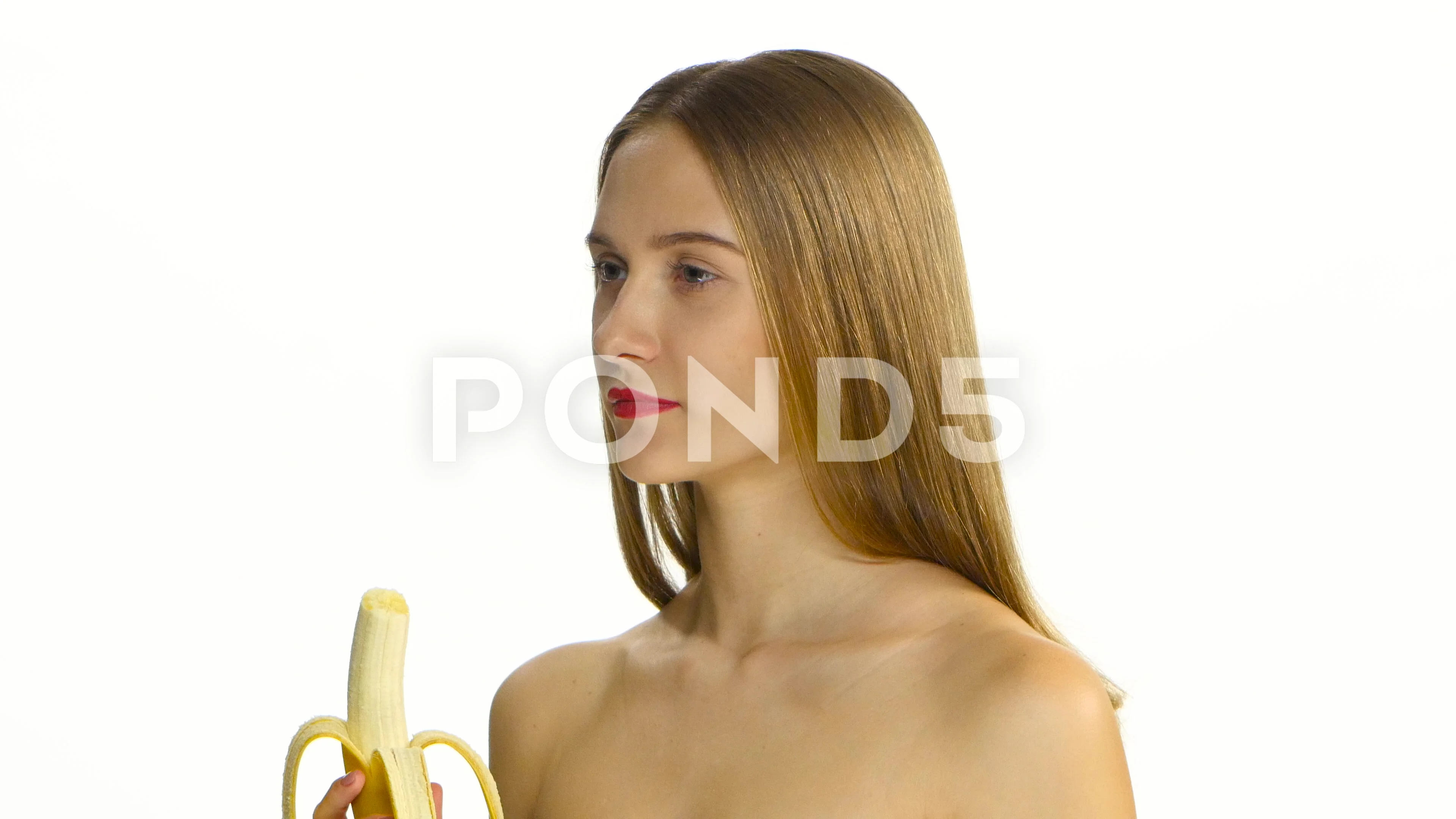 Girl with braces eating a big banana. White. Closeup