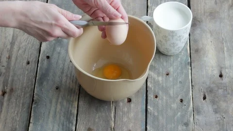 Girl Breaks An Egg Into bowl. Preparing ingredients for baking. Stock Footage