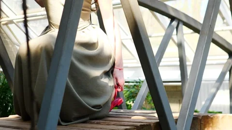 A girl on a bridge elegantly adjusts her shoes Stock Footage 310539993