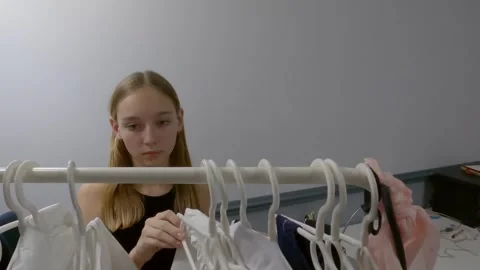 Girl browsing clothes on rack selecting outfit from wardrobe Video stock 338053177
