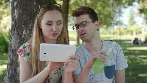 Girl browsing internet on tablet and chatting with her friend in the park, stead Stock-Footage 78625966