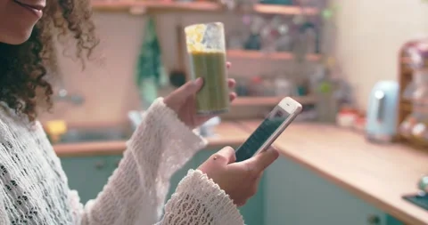 Girl browsing on social media while enjoying her green smoothie Stock Footage 198357010