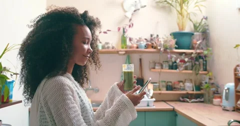 Girl browsing on social media while enjoying her green smoothie Stock Footage 198360184