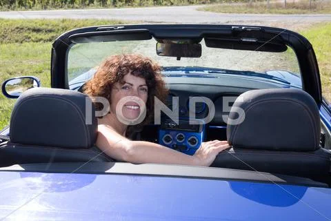 Girl brunette, happy in blue cabriolet driving on road trip Stock Photos