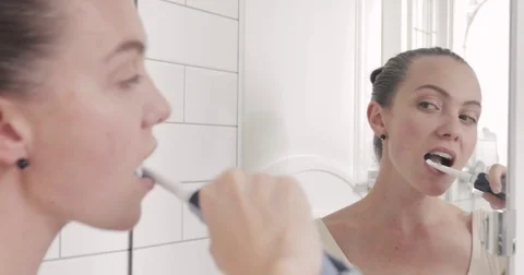 Girl brushes her teeth with electrical toothbrush Stock Footage