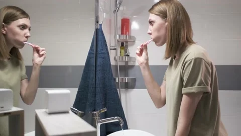 The girl brushes her teeth. Reflection in the mirror. Stock Footage 150989247