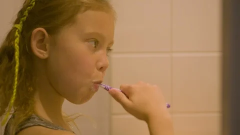 GIRL BRUSHING TEETH in front of mirror Stock Footage 89756548
