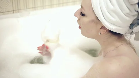 Girl in a bubble bath slowly drinks champagne Stock Footage 124622625