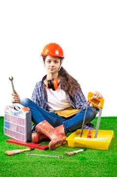 Girl builder holding a construction tools sitting on the grass Stock Photos