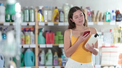 Girl buyer scans qr code on shampoo or shower gel label Stock Footage 310067431