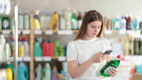 Girl buyer scans qr code on dishwashing soap label Stock Footage 313099149
